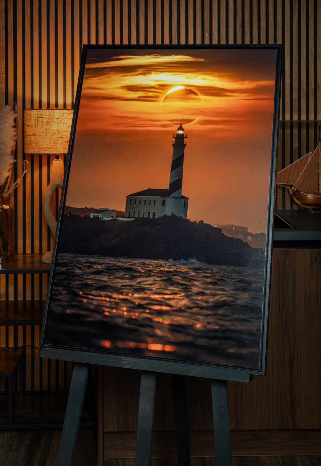 The framed print of The Lighthouse Eclipse on an easel in the gallery